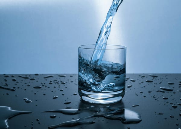 Transparent glass being filled with clear blue water